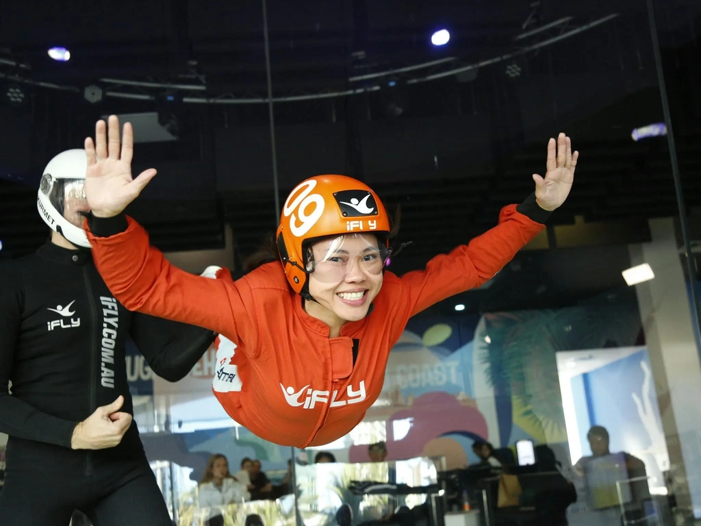 Female first time flyer in an orange suit with a massive smile.