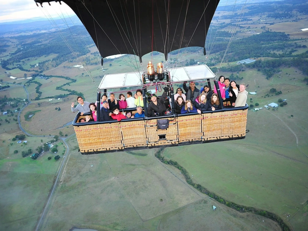 Hot air balloon drifting over hinterland farmland