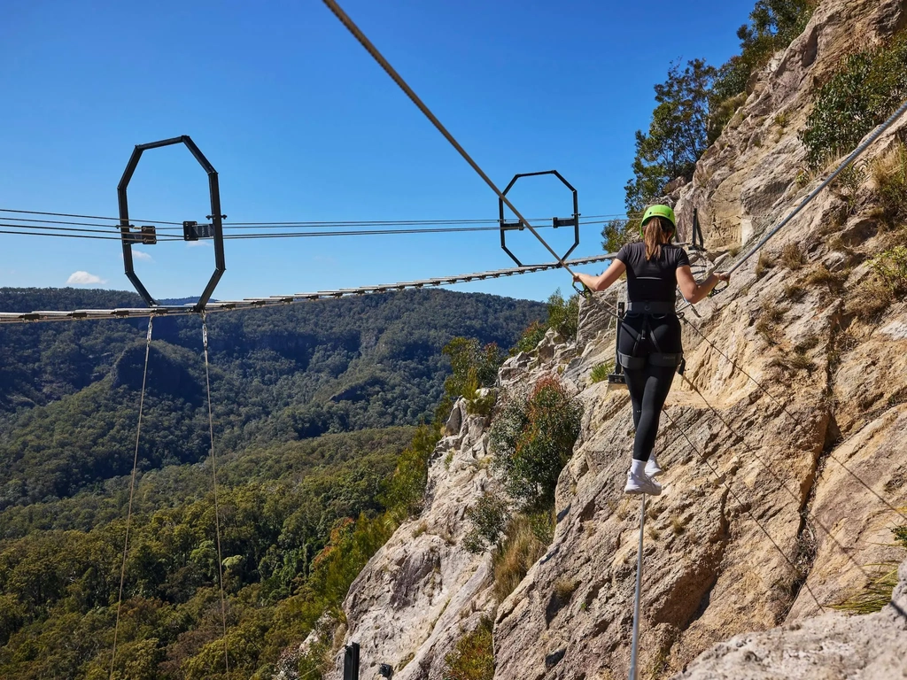 Woman walking across Via Ferrata at Happitat Adventure Park