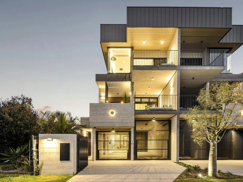 Three storey concrete and timber holiday house lit at twilight