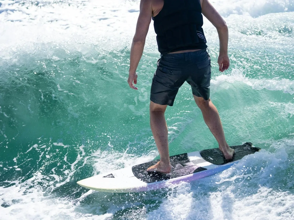 Close up of a crystal clear blue water peeling wave with a wake surfer living his best life