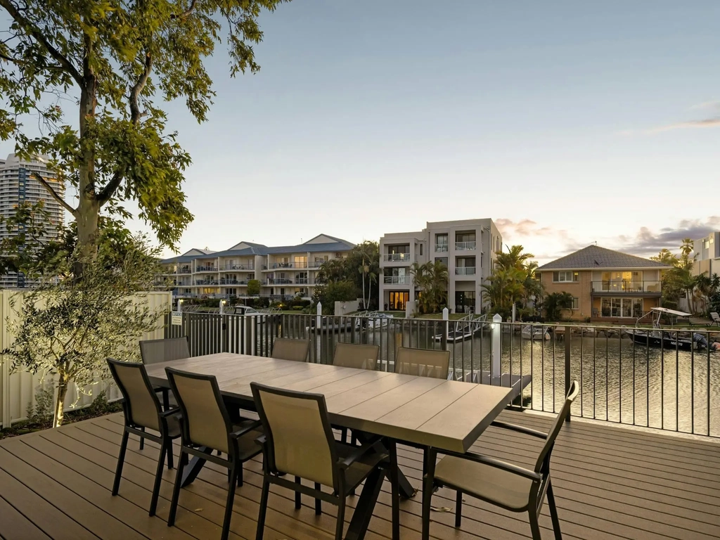 Timber deck with outdoor dining beside a canal and boat moorings