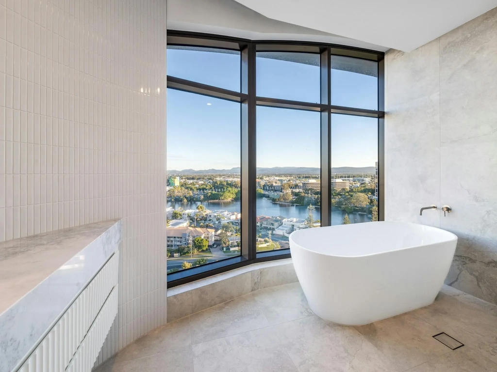 Freestanding bath in a corner of glazing with river and hinterland views