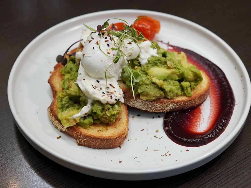 A breakfast order with smashed avocado and poached eggs on toast