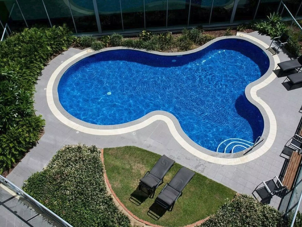 Outdoor swimming pool with lush garden areas and places to relax