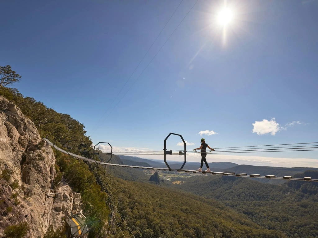 Woman walking across Via Ferrata at Happitat Adventure Park