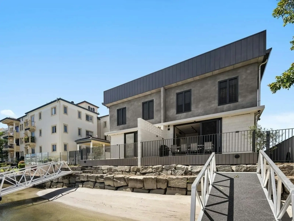 Water frontage with rock seawall, sand and a gangway to the private pontoon