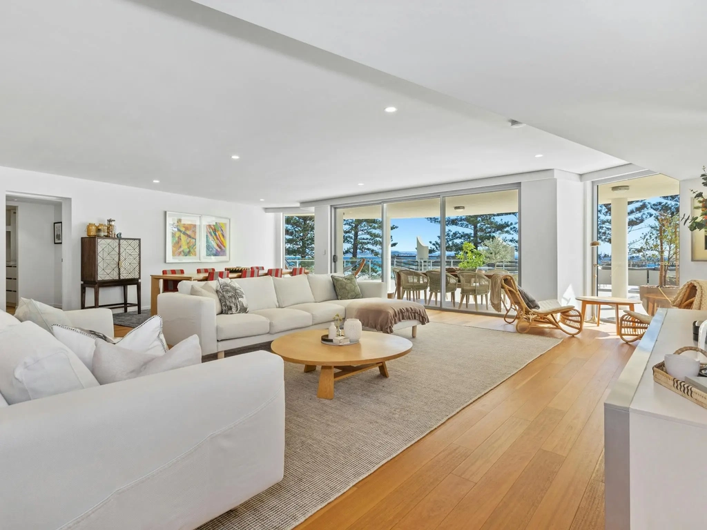 Spacious lounge in Apt 402 featuring timber floors, neutral sofas, chaise lounge, and ocean views.