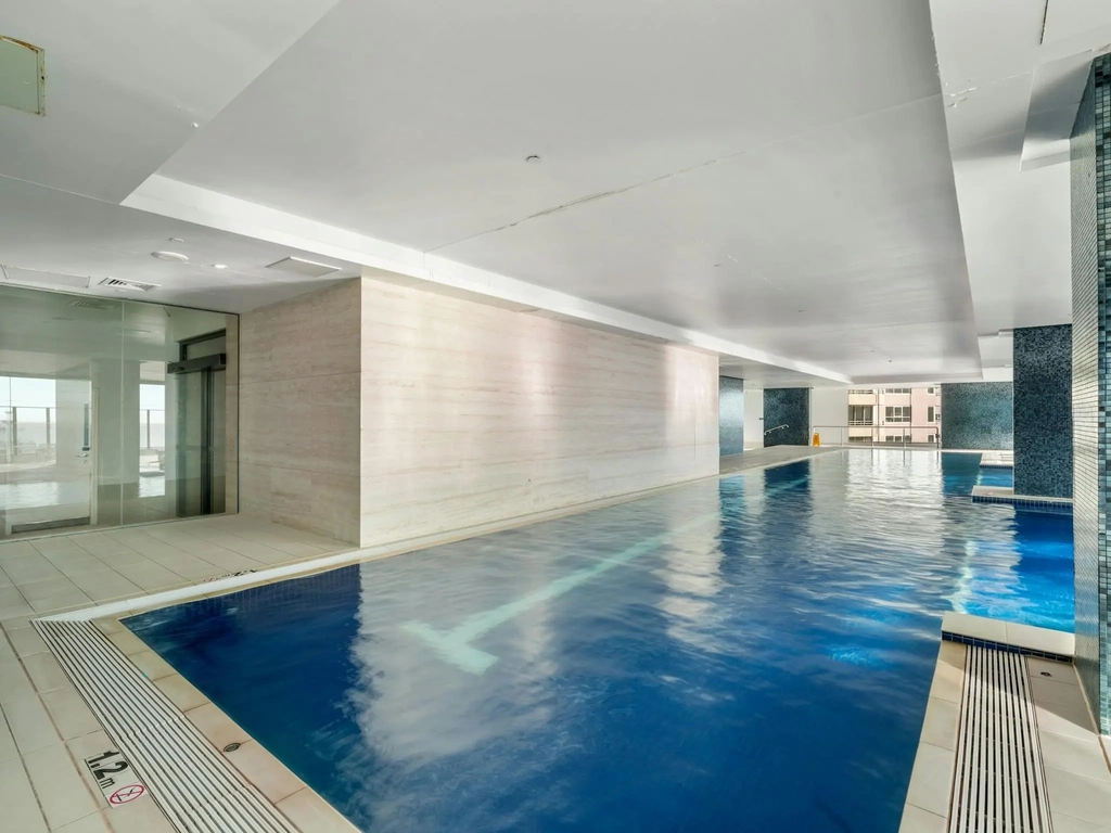 Indoor lap pool with tiled surrounds inside the building.