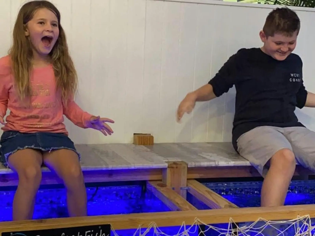 Two children laughing as they have a fish spa at Barefoot Fish