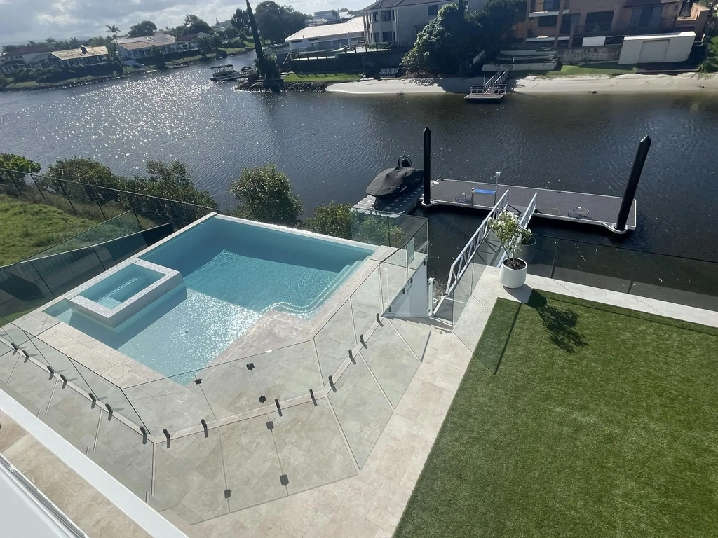 Infinity edge swimming pool and raised spa beside a canal