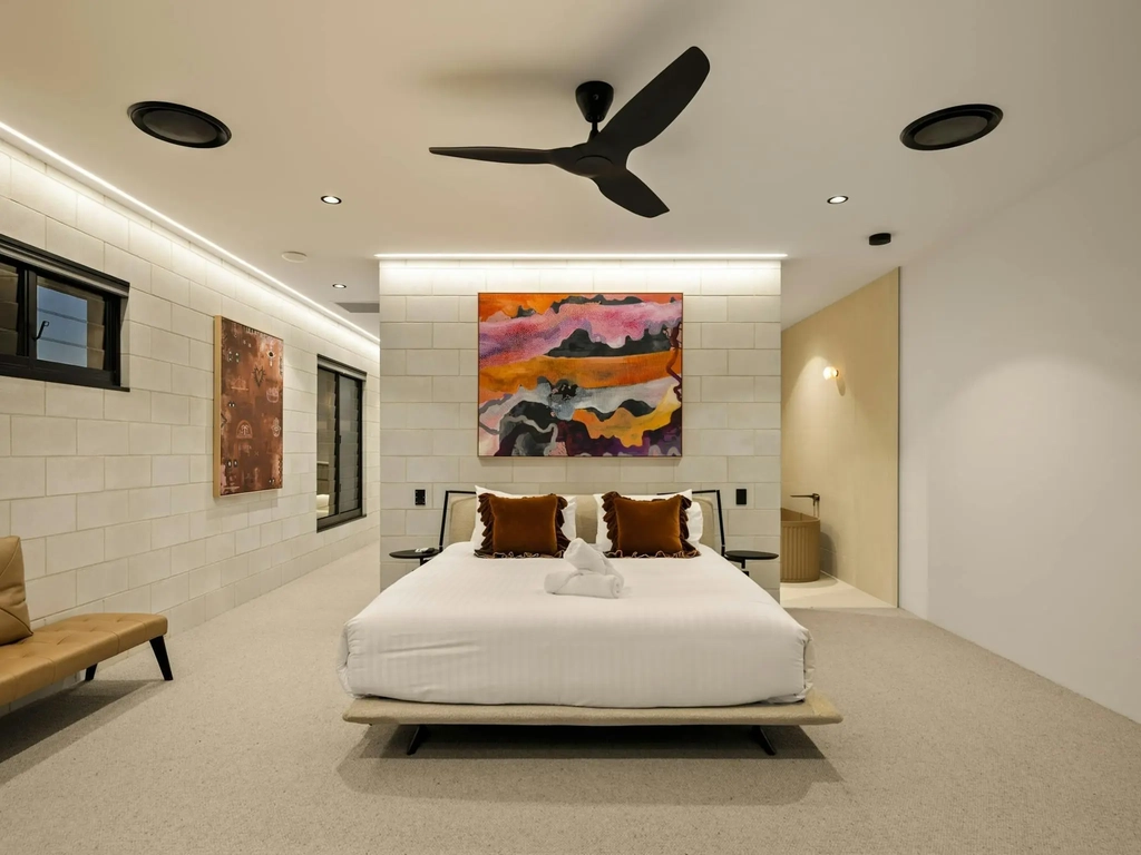 Carpeted bedroom with a leather bench seat and artwork