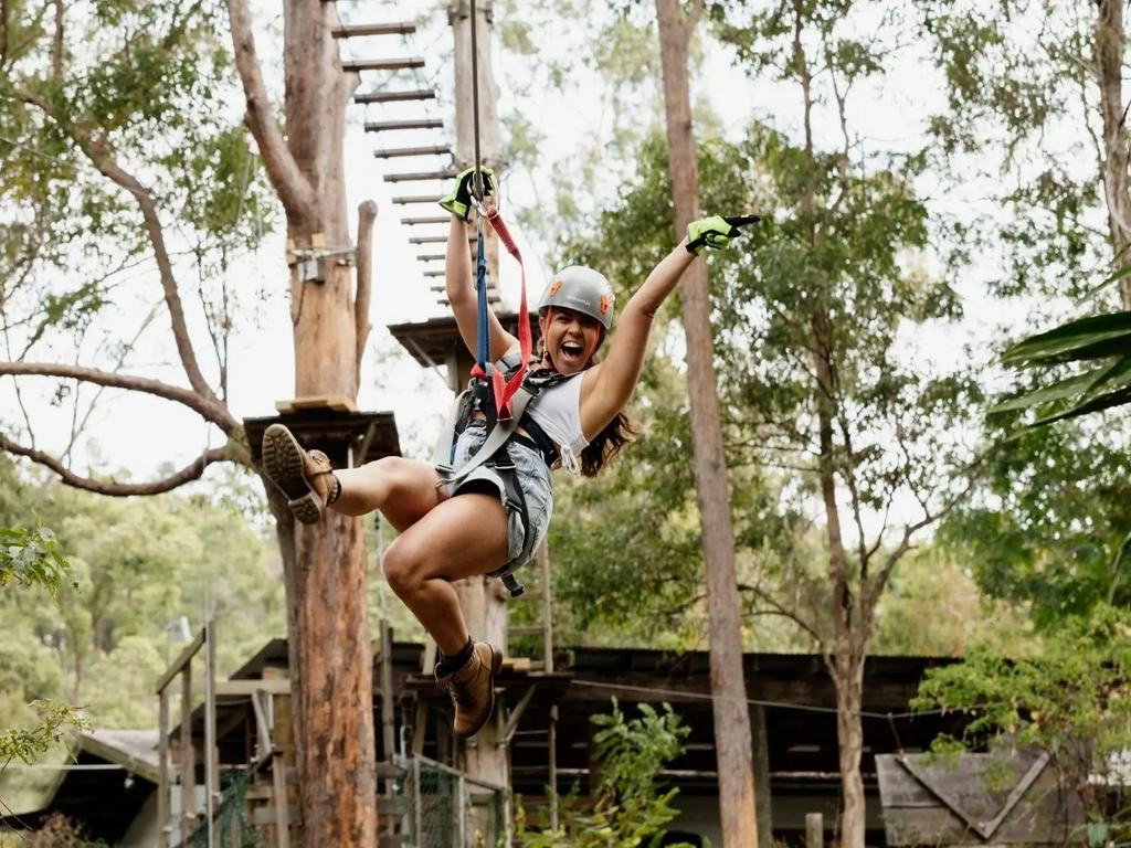 Woman ecstatic as she flies across a zipline.