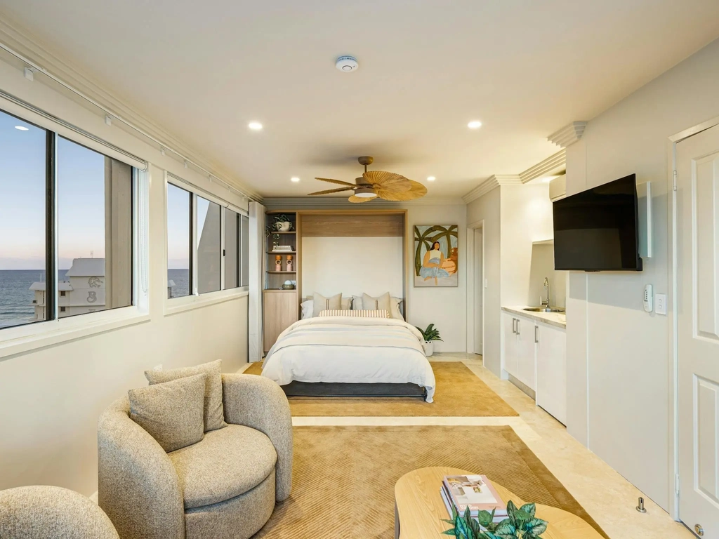 Upstairs bedroom with a fold-down queen bed, armchairs, kitchenette and ocean windows
