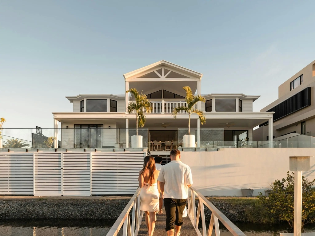 Two storey white house viewed from a private pontoon at golden hour