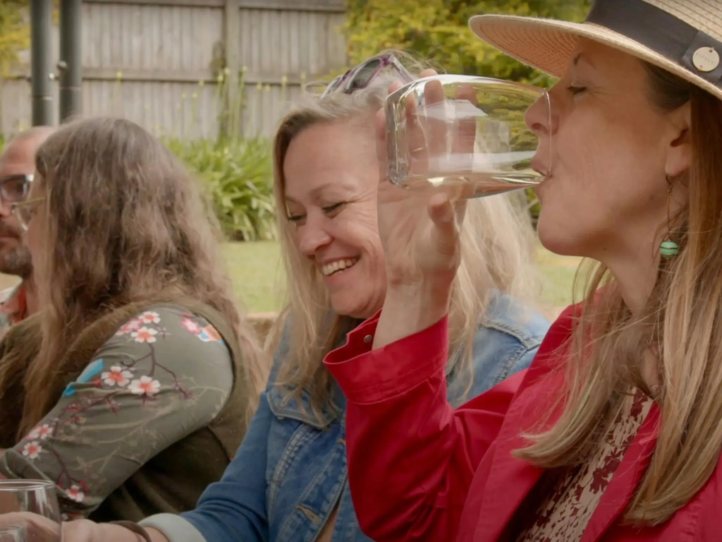 A group of women sitting at a winery smiling and sipping wine