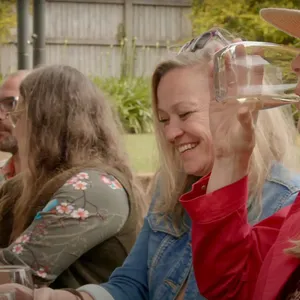 A group of women sitting at a winery smiling and sipping wine