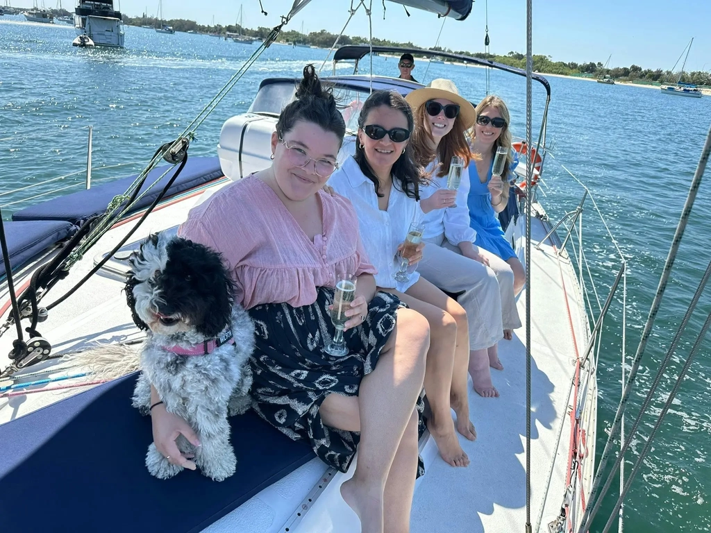 Four women sitting on yacht enjoying a sparkling wine with Spoodle during a Sun Sailing charter