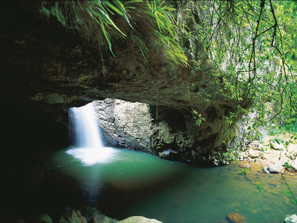 White water cascades down a rockface into a green rockpool