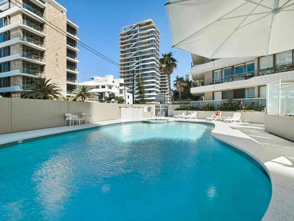 Shared swimming pool in the building grounds with sun lounges