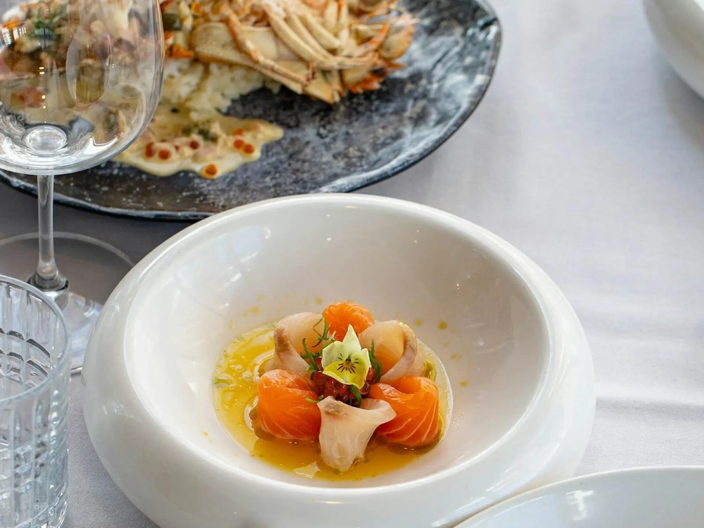 Shared dishes and crudo on the table at River House waterfront restaurant, Southport.