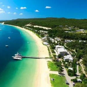 Boat at a jetty and a resort situated on a sandy beach and turquoise water