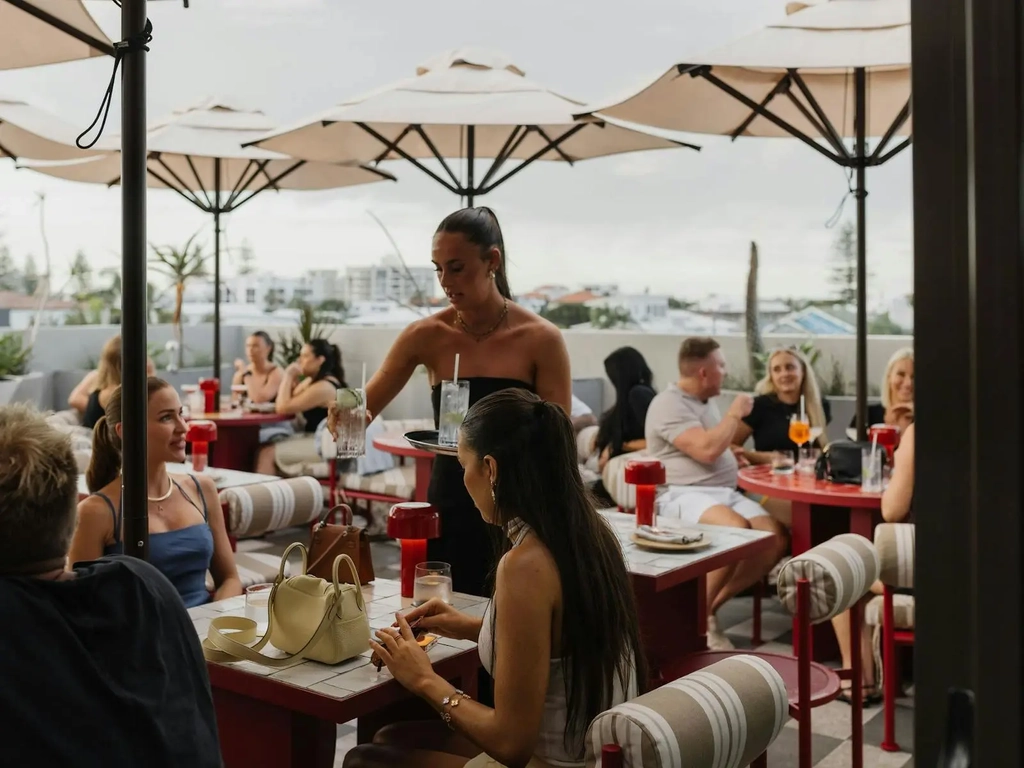 A full rooftop with people being served drinks