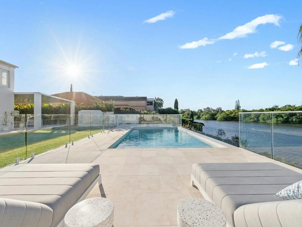 Swimming pool beside a canal at sunset with sun lounges