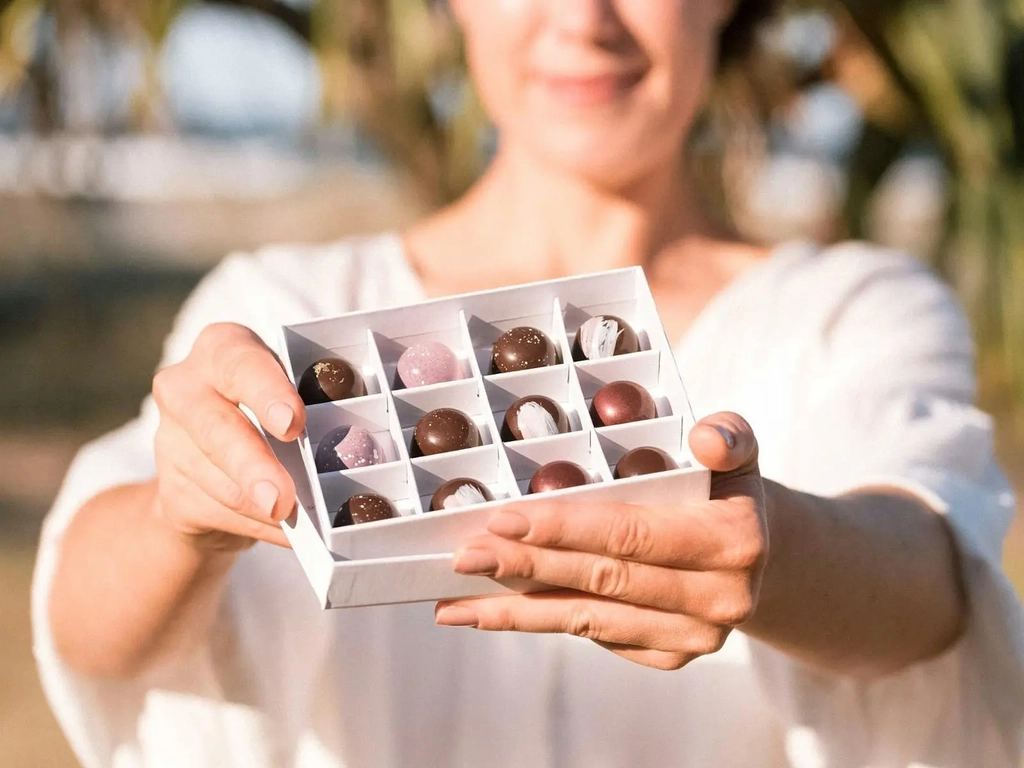 Woman holding an open box of chocolates in front of her