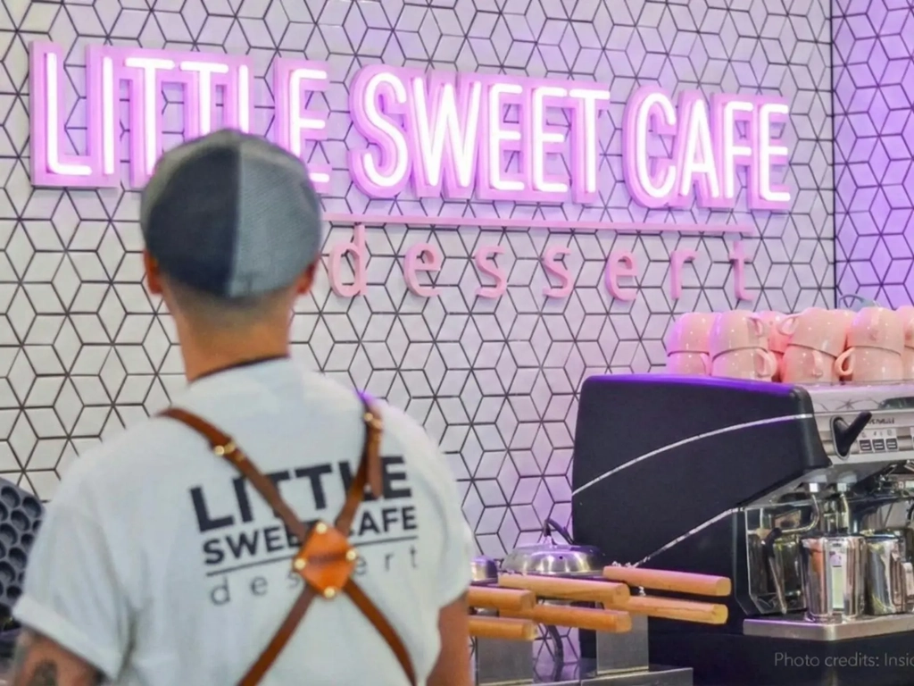A man from Little Sweeet Cafe is crafting bubble waffle and making coffee