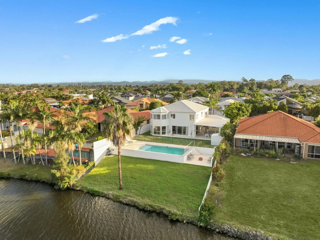 Aerial view of a canal-front residence with pool and lawn in Robina