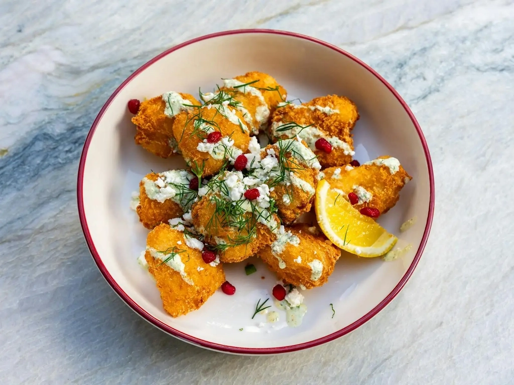 Golden crumbed share plate with dill, feta, pomegranate and a lemon wedge