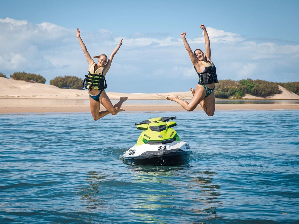 Two girls jumping off a jet ski