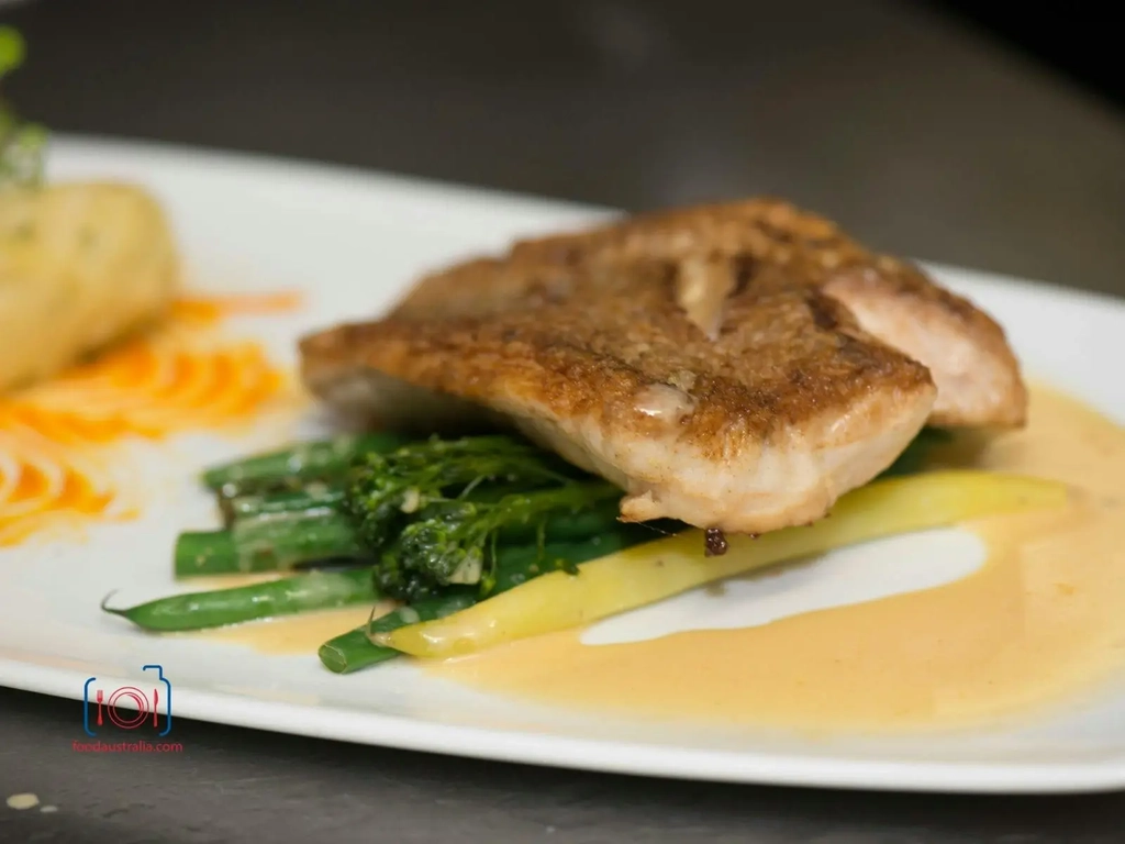 Locally sourced fish on white plate with green beans and sauce