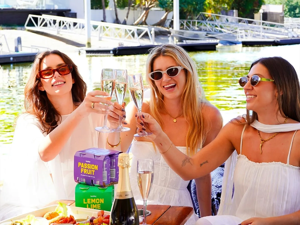 Three women toasting drinks aboard a luxury-style GoBoat picnic experience on the Gold Coast.