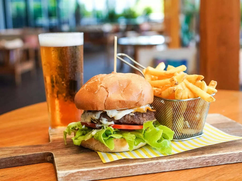An image featuring a burger, chips & beverage