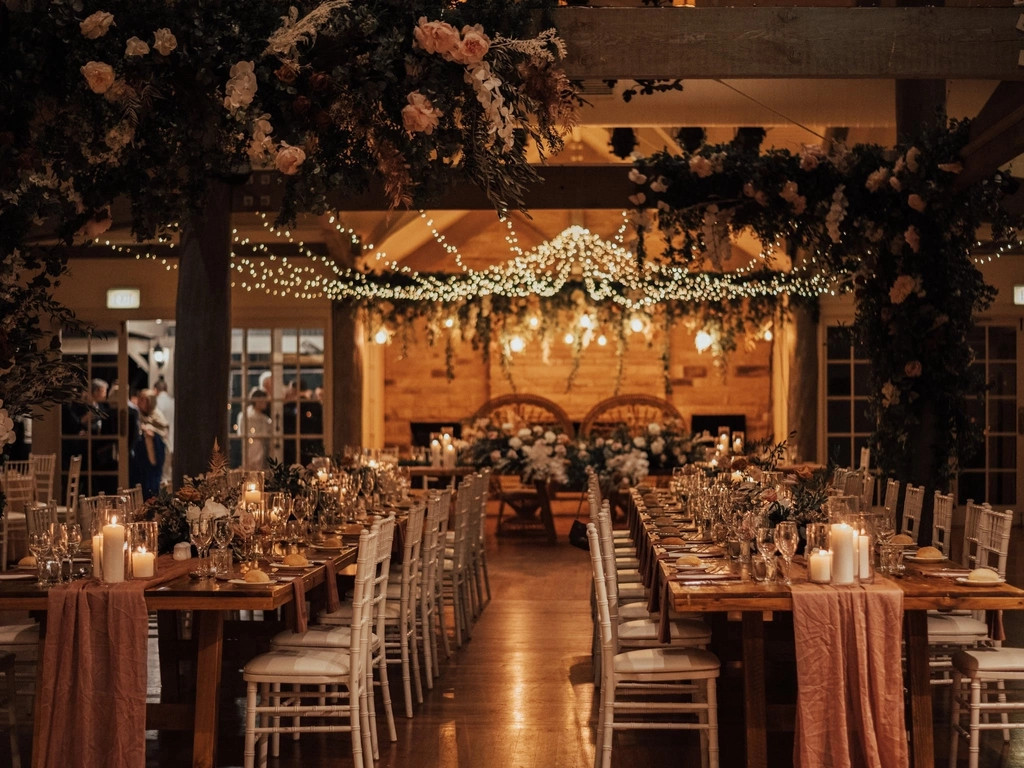 A wedding reception with fairylights in the ceiling, long timber tables and romantic candles.