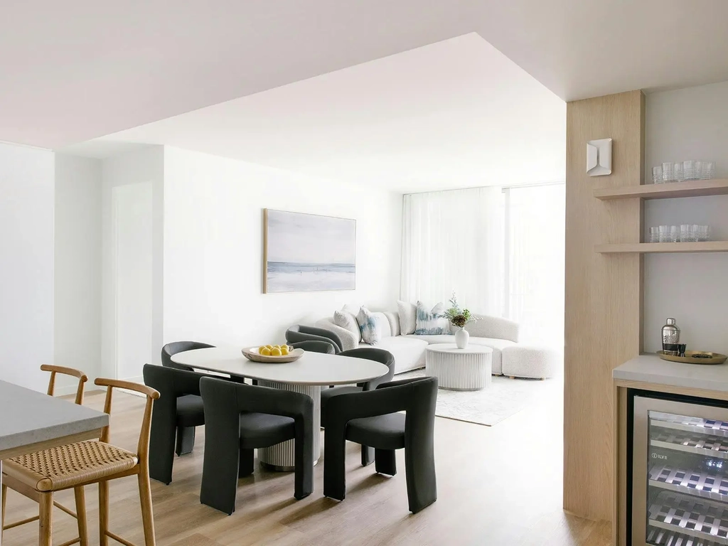 Elegant Kirra Point dining and lounge area with bar fridge, ocean artwork, and soft natural light.