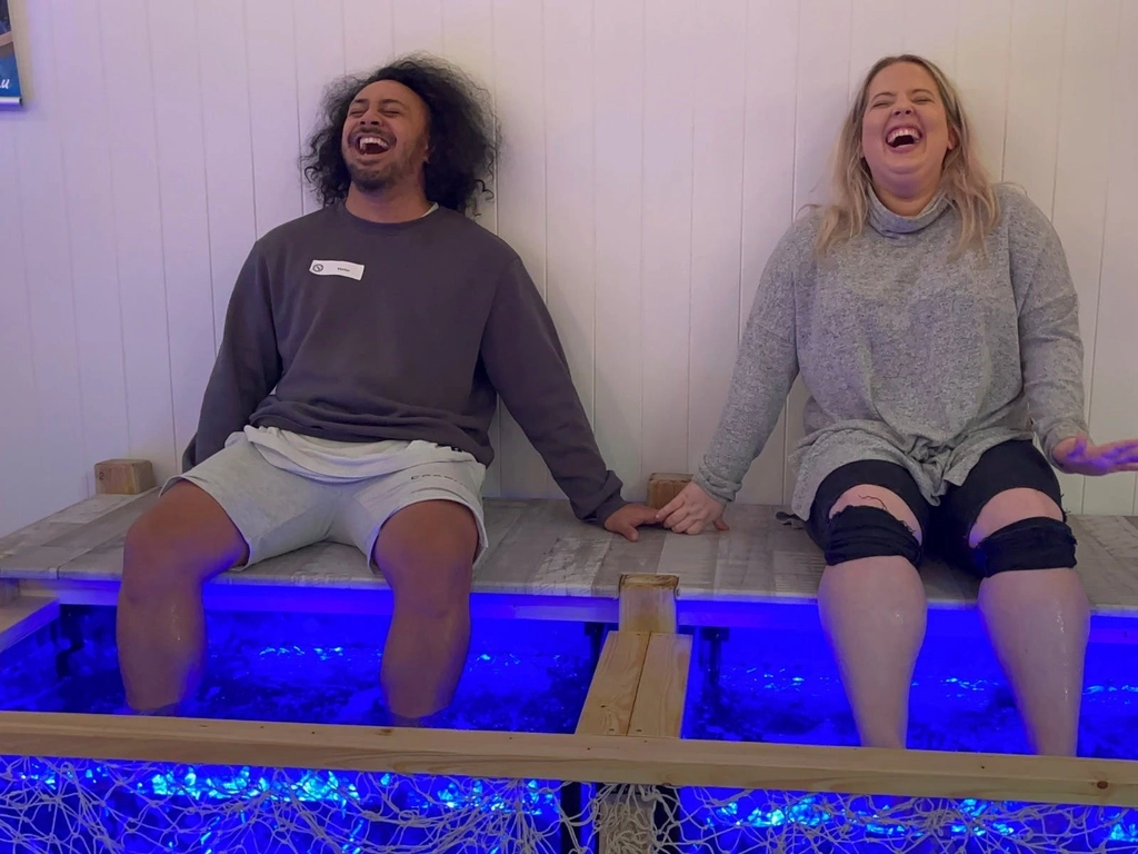 Two people laughing as they enjoy their fish spa at Barefoot Fish