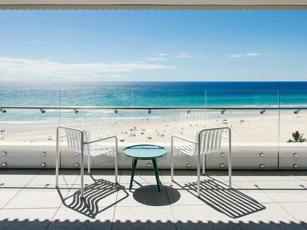 Private Kirra Point balcony with ocean views, beach access, and seating for two under blue skies.