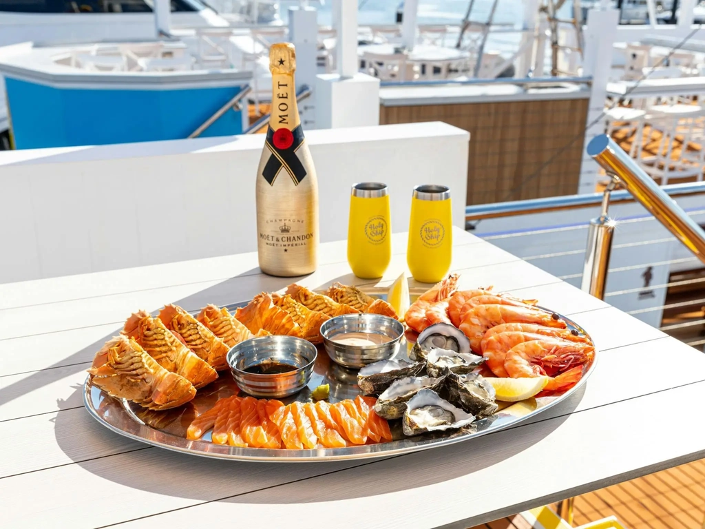 A seafood platter containing oysters, bugs, prawns and salmon sashimi with a bottle of champagne