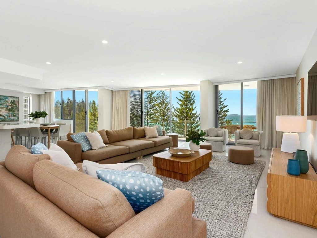 Warm, inviting lounge featuring two large tan lounges, elegant decor, and breathtaking ocean views