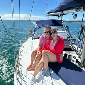 Lady in red and man in pink sitting on the deck of Sun Sailing's yacht during a sunset shared cruise