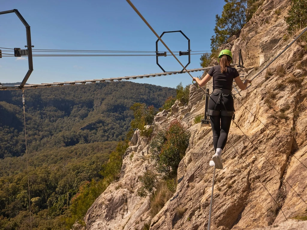 Woman walking across Via Ferrata at Happitat Adventure Park