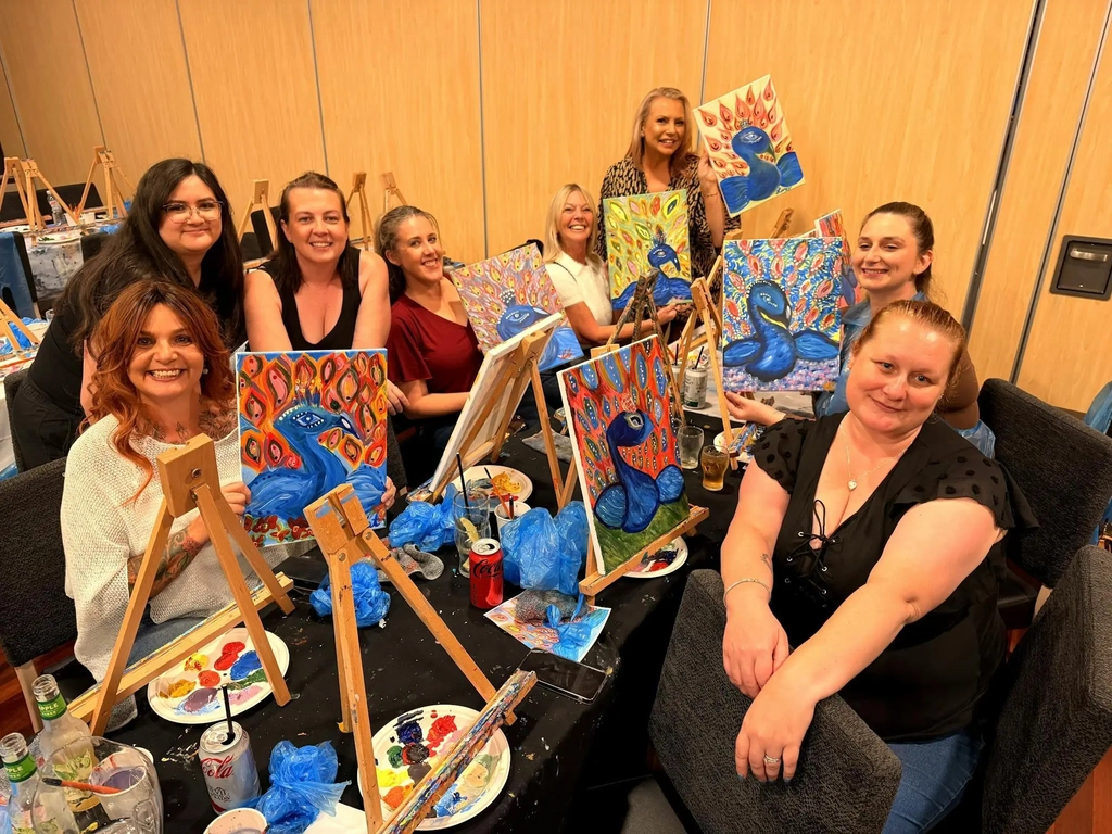 Paint Juicy guests painting at a table of canvases and palettes during a mobile paint and sip sessio