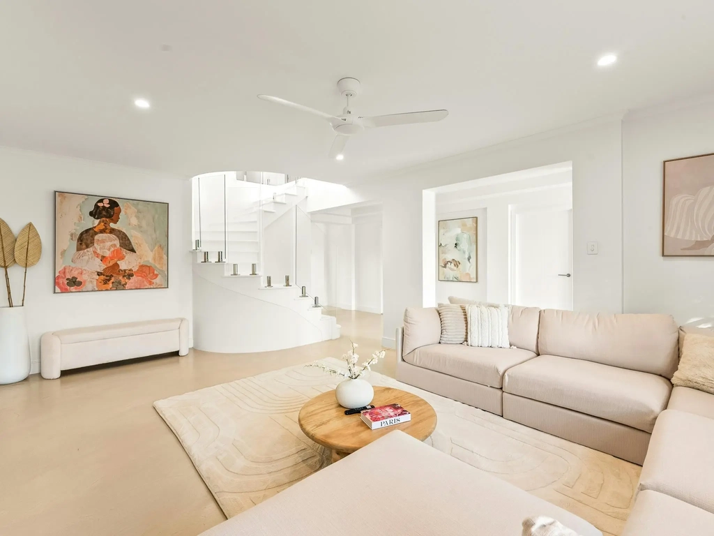 Open living area with a curved staircase and neutral furnishings