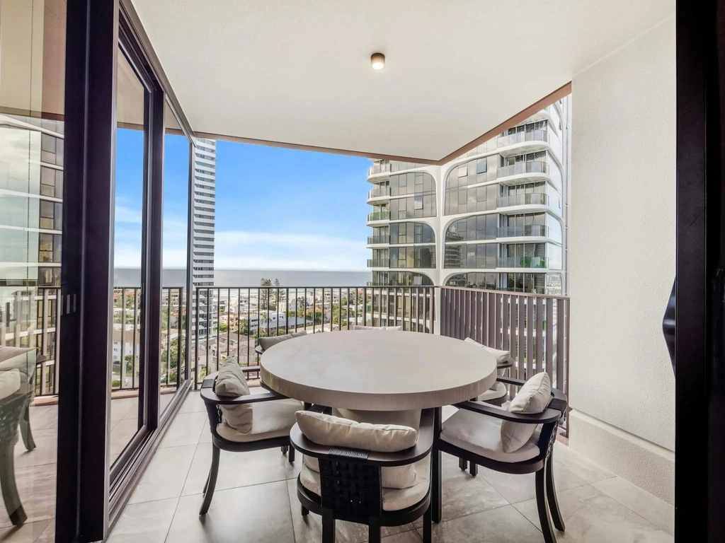 Covered balcony with a round outdoor dining table for four and ocean views.