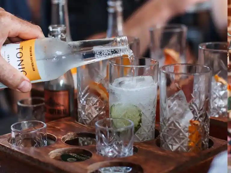 A photo of someone pouring tonic into their gin tasting flight.