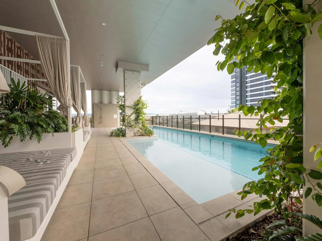 Outdoor swimming pool on the building recreation deck with shaded cabanas.