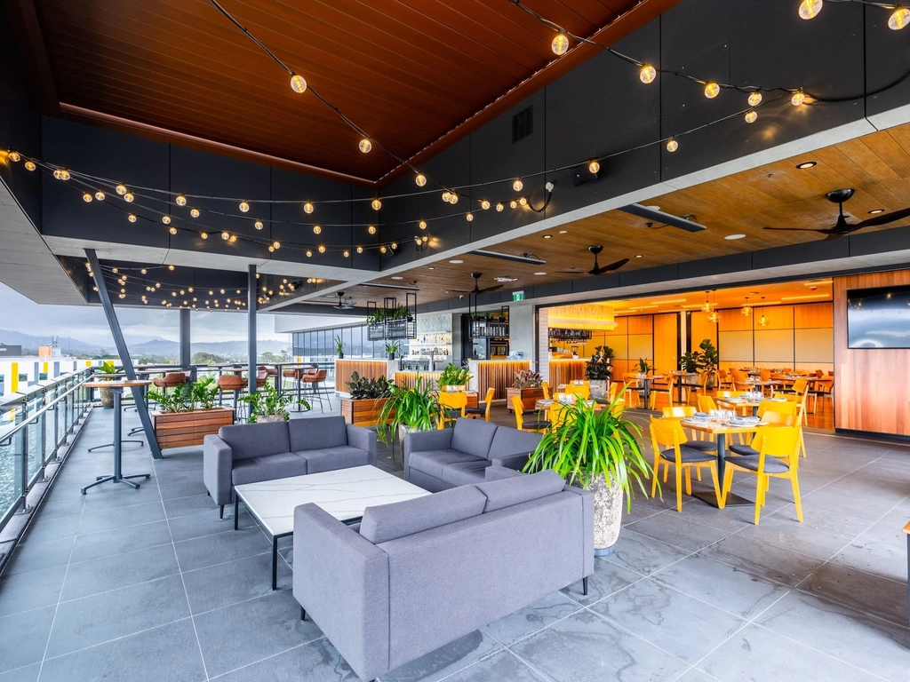 Rooftop area with lounges and tables, festoon lights and hinterland views